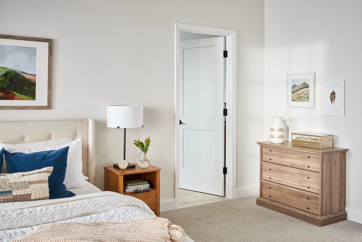 a light blue 2 panel logan door in a primary bedroom leading into a bathroom